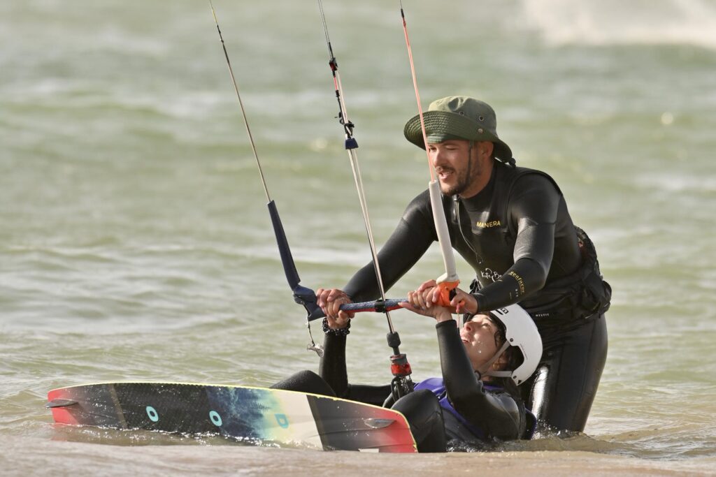 Moniteur aidant un élève à se placer sur la planche dans l’eau wingfoil essaouira | moniteur aidant un élève à se placer sur la planche dans l’eau | 4