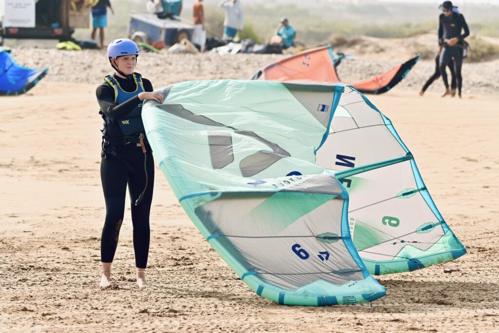 Élève dépliant une aile sur le sable à Essaouira wingfoil débutant | élève dépliant une aile sur le sable avant la séance | 2