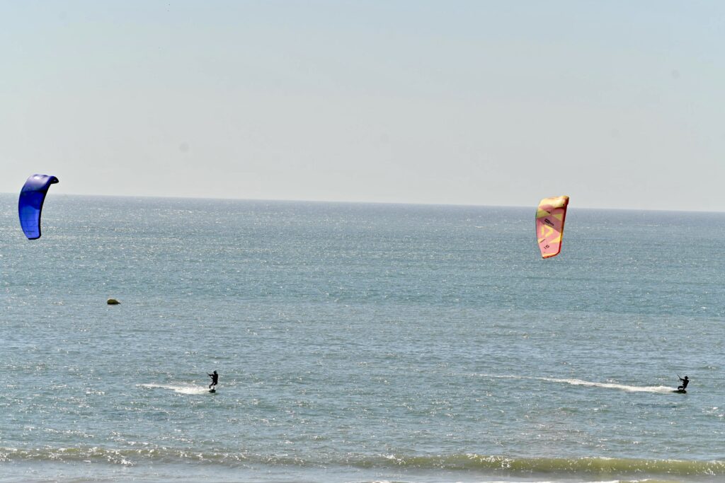 stage wingfoil Maroc | riders au large sous des kites bleu et rose | 3