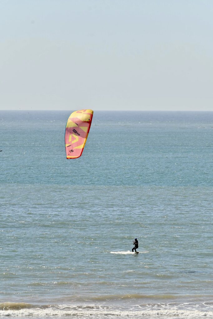 Kitesurfeur sous un kite coloré à Essaouira séjour wingfoil | kitesurfeur au loin sous un kite coloré à Essaouira | 3